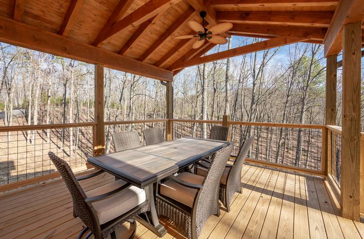 cabin deck with dining table and wooded view
